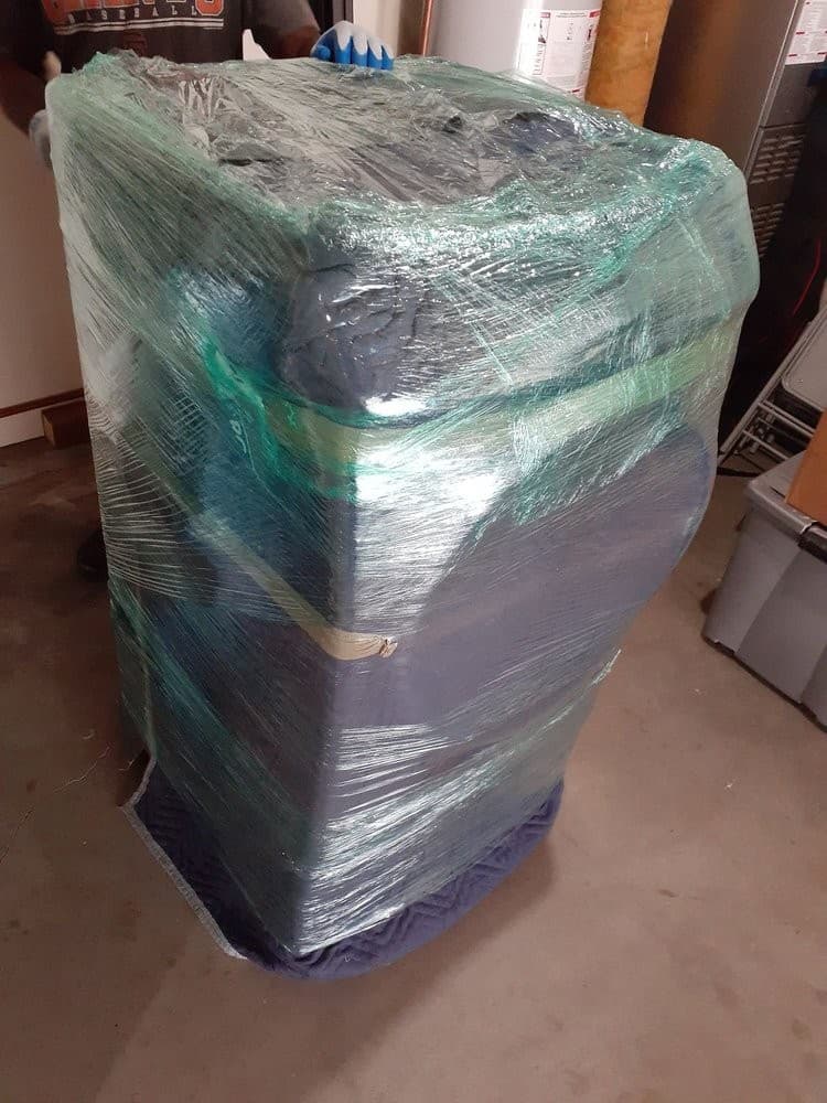 Large appliance wrapped fully in protective blankets and plastic for transport.