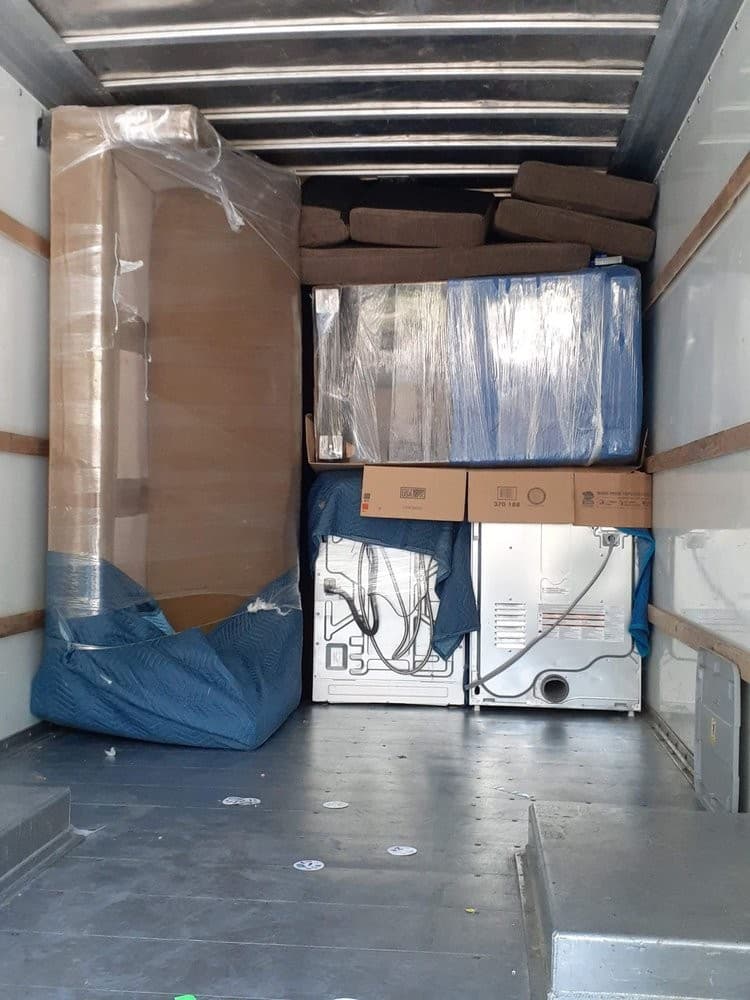 Efficient moving truck loading with wrapped appliances and furniture protected by moving blankets.